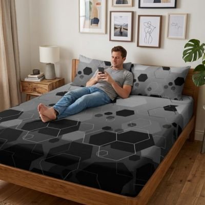 Drap housse confort élastique homme allongé sur son lit les pieds croisés concentré sur son téléphone