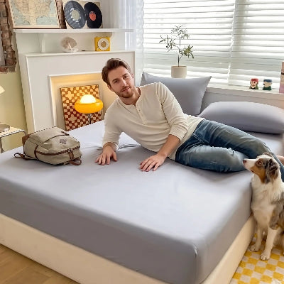 Drap housse gris clair jeune homme apprécie le confort de son lit accompagné de son chien