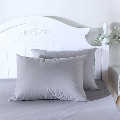 Taie d'oreiller premium confort gris appuyé sur tête de lit blanche 