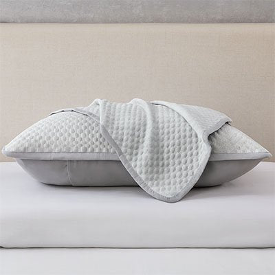 Taie d'oreiller premium texture gris avec un oreiller habillé de sa taie d'oreiller et une autre taie simplement posée dessus